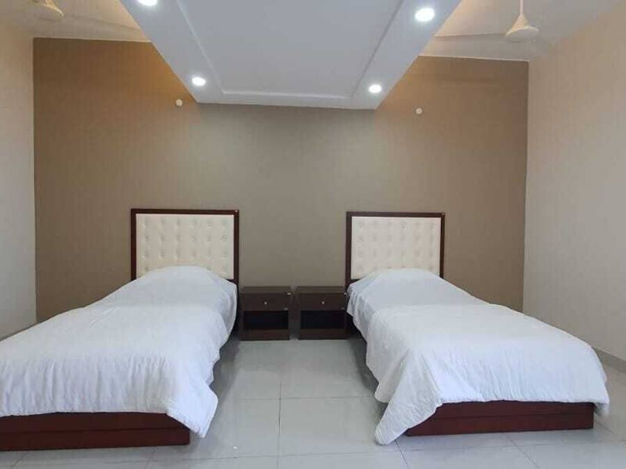 A twin room with two beds, a door, and a red mat on the floor.