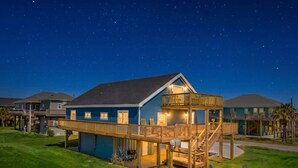A two-story building with a balcony, a deck, and a fire pit area. - Cozy Beach House with Game Room, Near the Beach (Crystal Beach)