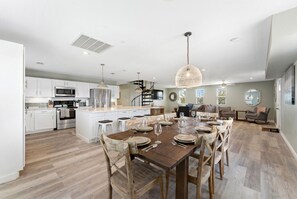 Une cuisine spacieuse dotée d’appareils électroménagers modernes, un coin repas avec des chaises en bois et un escalier menant à l’étage supérieur.