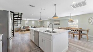 A modern kitchen with a central island, stainless steel appliances, and pendant lighting. - Cozy Beach House with Game Room, Near the Beach (Crystal Beach)
