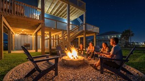 A deck with a fire pit, seating, and a covered area with railings. - Cozy Beach House with Game Room, Near the Beach (Crystal Beach)
