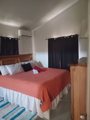 A bed with a red and white bedspread, a wooden headboard, and a bedside table with a lamp.