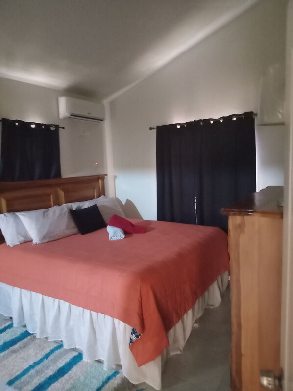 A bed with a red and white bedspread, a wooden headboard, and a bedside table with a lamp.