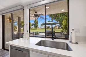 Cozinha com uma janela grande, ventilador de teto e vista para um campo de golfe.