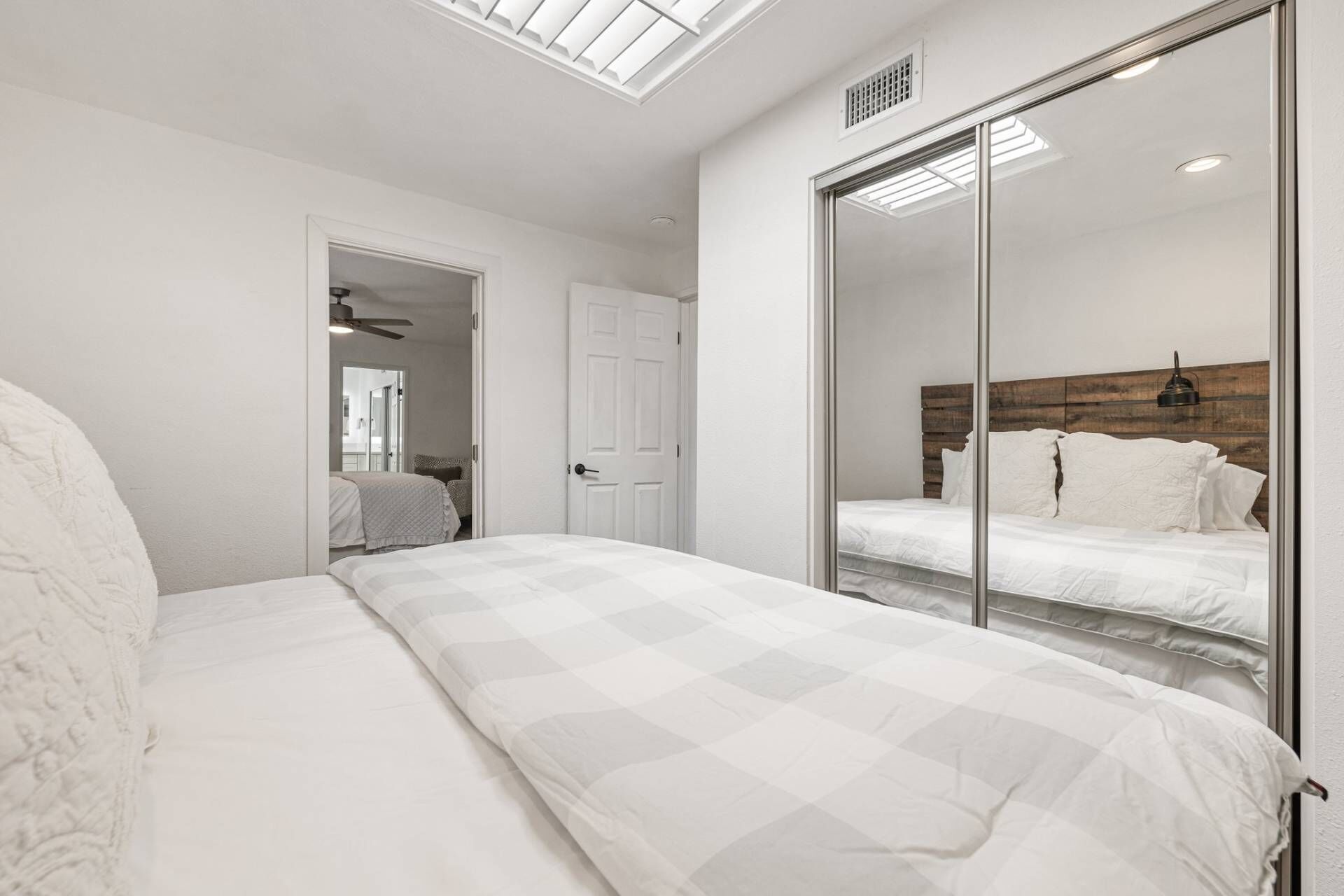 Une chambre avec un grand lit, une armoire avec un miroir et un ventilateur de plafond.