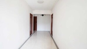 A narrow, white-walled hallway with a tiled floor leading to a door at the end. - Cozy Double Stay | Near Suvarnabhumi Airport Hub (Bangkok)