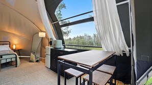 A cozy tented room with a bed, a table, and a chair, a small desk, and a lamp. - Escape to Cloud Nine Glamping in the Black Hills (Hermosa)