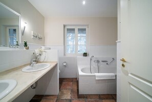 A bathroom with two sinks, a bathtub, and a window. - Familienhaus fur in Dierhagen (Ostseebad Dierhagen)