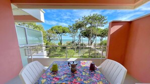 A balcony with a table set for two, featuring a colorful tablecloth and two cups.