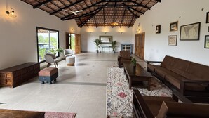 Amplia sala de estar con techo alto, vigas de madera y un gran ventanal con vistas a la vegetación.