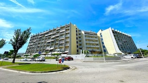 A multi-story hotel with a modern design, featuring balconies on each floor, located at a street corner with a clear blue sky. - Holiday Home in Caorle near Spiaggia Tartaruga (Porto Santa Margherita (VE))