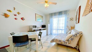 A room with a bed, a desk with a computer, a TV, and decorative fish on the wall. - Holiday Home in Caorle near Spiaggia Tartaruga (Porto Santa Margherita (VE))