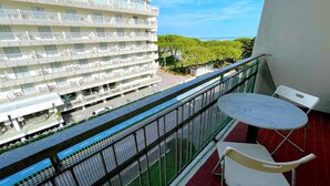 A balcony with a table and chairs, overlooking a modern building with multiple balconies and a view of the sea. - Holiday Home in Caorle near Spiaggia Tartaruga (Porto Santa Margherita (VE))