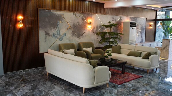 A modern living room with a sectional sofa, a coffee table, and decorative lighting. - Zeus Otel (Kusadasi)