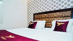 A hotel room with a large bed, a headboard with a patterned design, and a decorative pillow with a bird design.