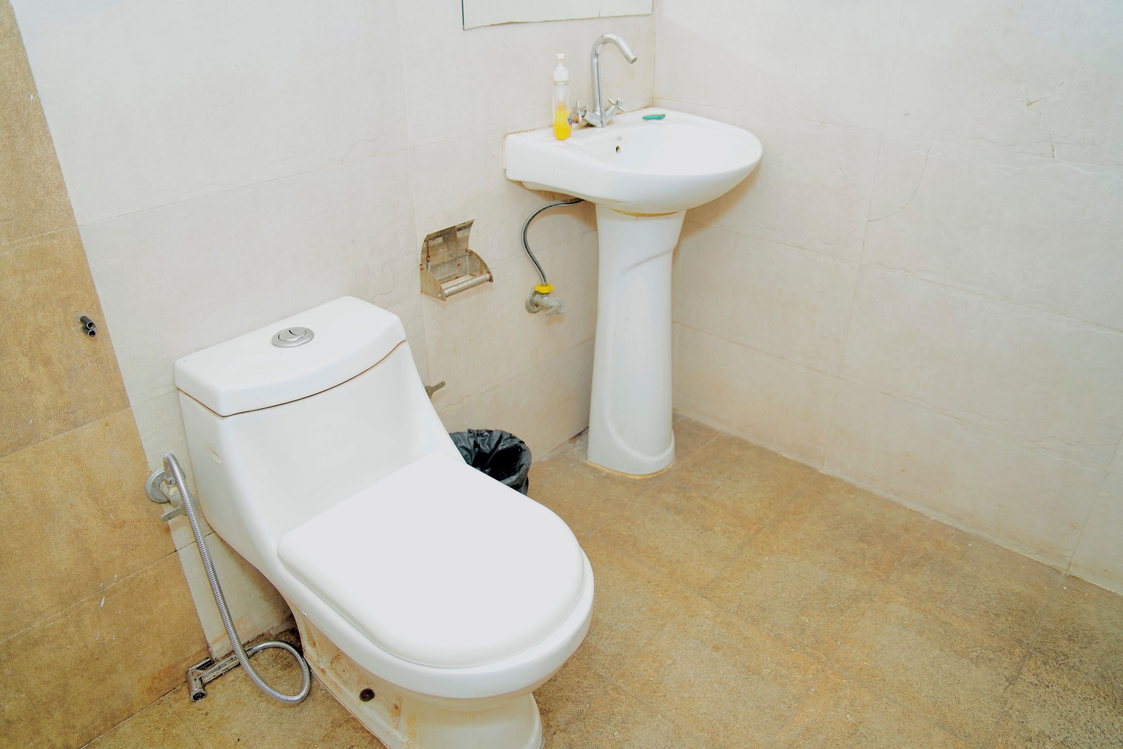 Een badkamer met een toilet, een wastafel en een prullenbak.