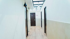 A narrow hallway with wooden flooring, white walls, and black doors.