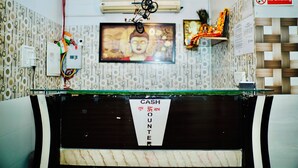 A reception area with a cash counter, a 'No Smoking' sign, a Buddha statue, and a wall-mounted air conditioner.