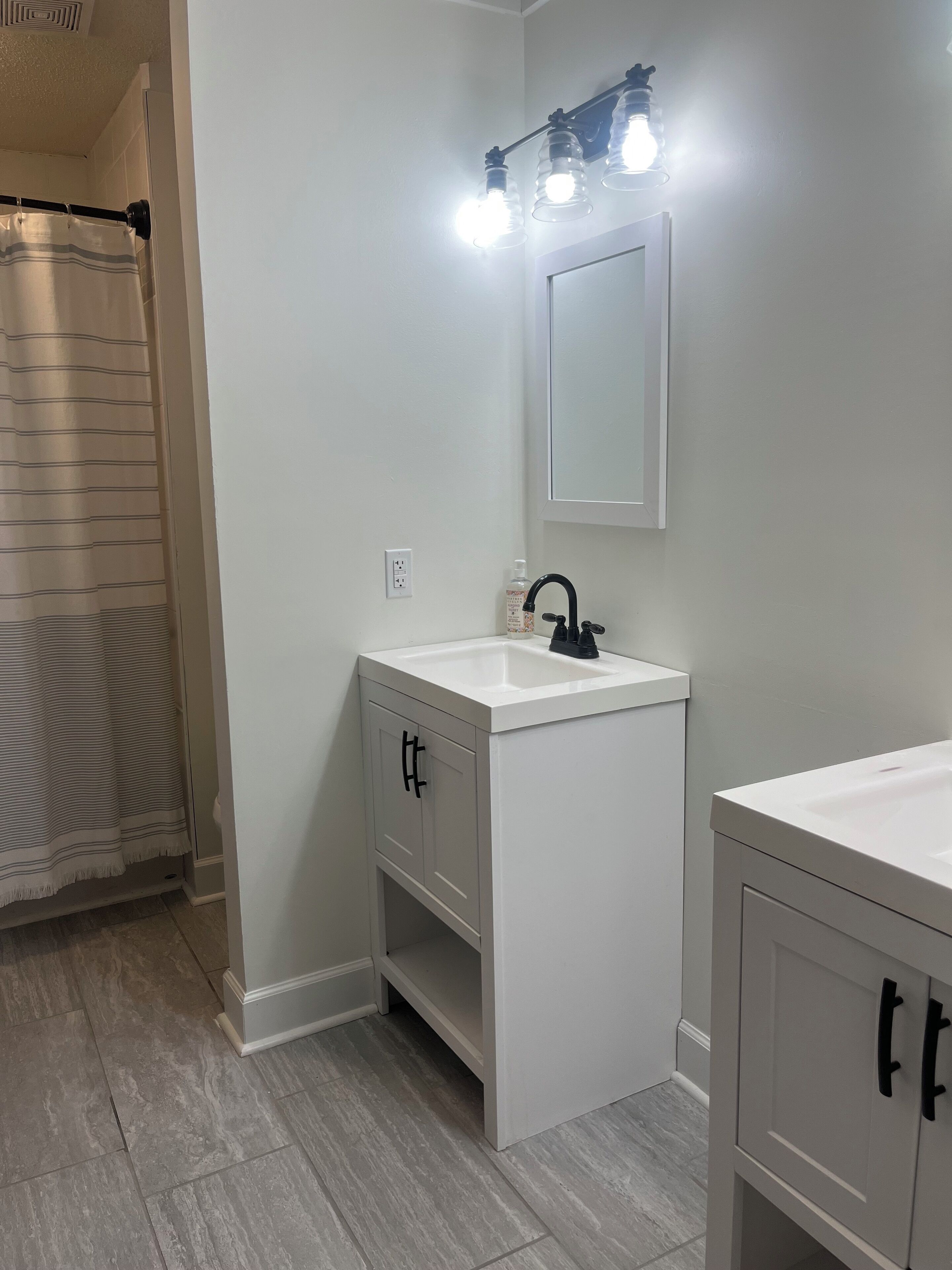 Une salle de bain avec un lavabo blanc, un miroir et un rideau de douche.