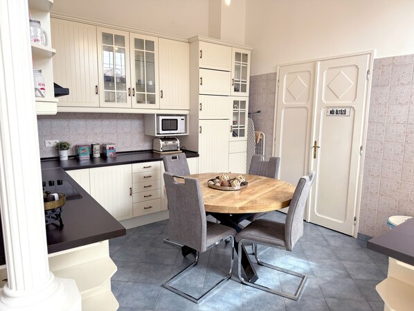 Une cuisine moderne avec des meubles blancs, un four à micro-ondes et une table à manger avec des chaises.