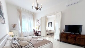 Un dormitorio moderno con una cama grande, un televisor y vistas al salón.