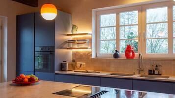 A modern kitchen with a built-in oven, a sink, and a window with a view of trees.