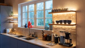 Una cucina con finestra, lavello, moka e diversi utensili da cucina.