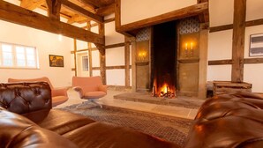 Una stanza con camino, divani in pelle e travi in legno.
