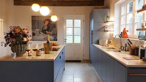 Una cucina moderna con isola centrale, travi in legno a soffitto e vista all'esterno.