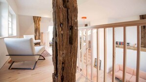 Un interno moderno con un baule di legno, una poltrona e una sedia rosa.