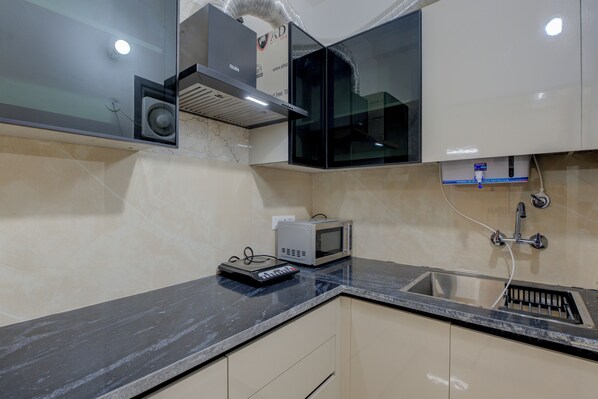 A kitchen with a microwave, a small appliance, and a sink. - aura homes 1bhk apartment (Gurugram)