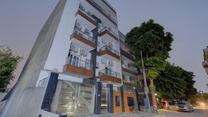 A multi-story residential building with balconies, air conditioning units, and a gated entrance.