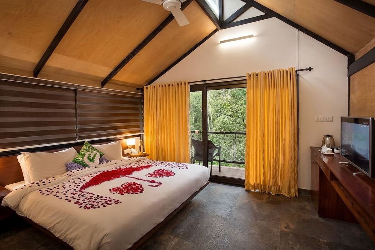 Un dormitorio con cama, mesita de noche, televisor y vistas a zonas verdes.