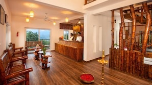 A spacious lobby with wooden furniture, a reception desk, and a view of the outdoors. - Bamboo Dale Resort (Udumbanchola)