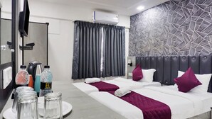A hotel room with two beds, a TV, a coffee machine, and a minibar. - Hotel Orchard Park (Pune)