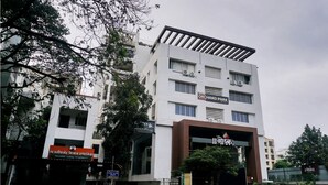 A multi-story hotel with a modern design, featuring a prominent entrance and signage for 'Hotel Orchard Park'. - Hotel Orchard Park (Pune)