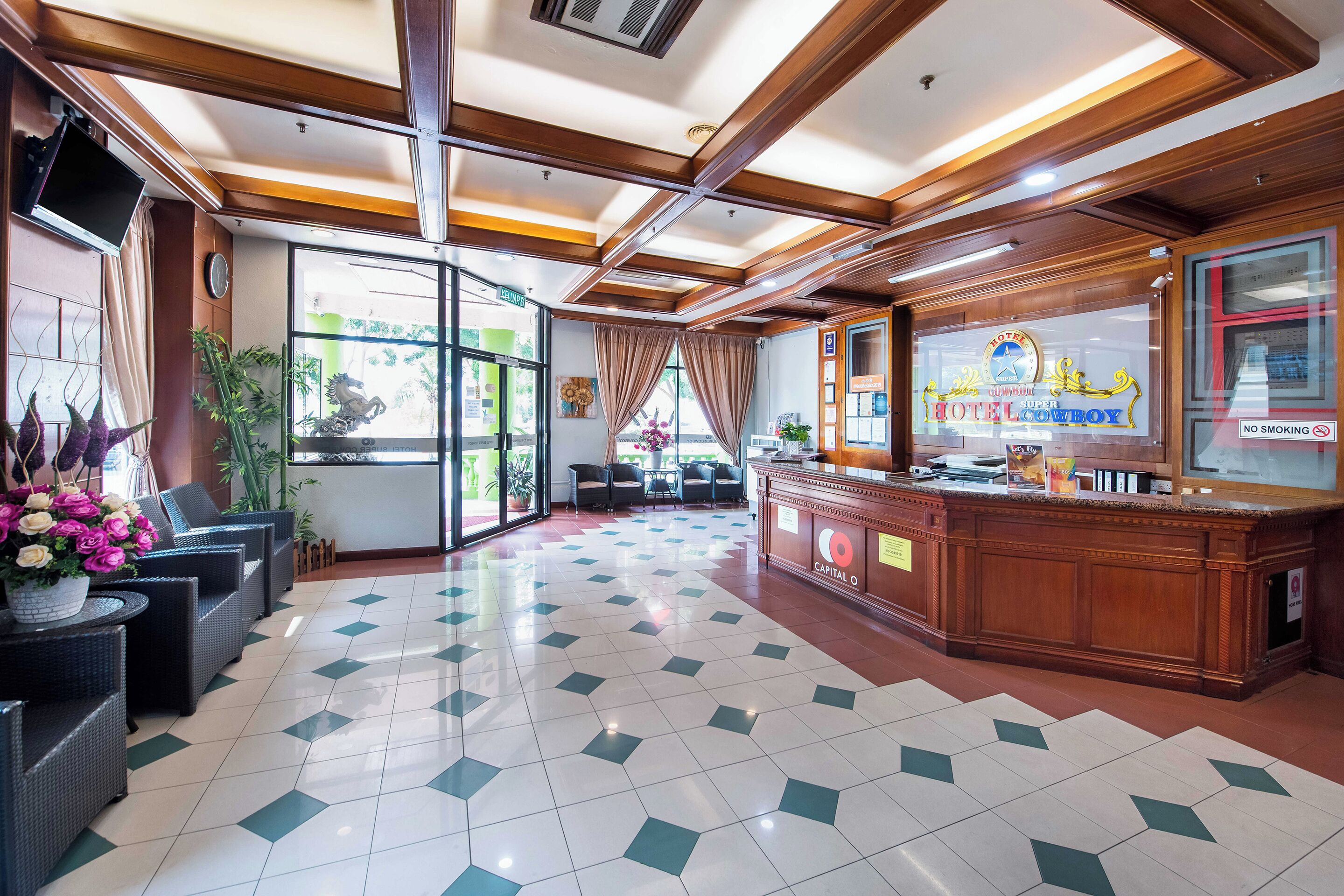 A hotel lobby with a reception desk, seating area, and a large window offering a view of the outdoors.