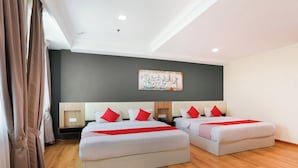 Una habitación de hotel con dos camas, un cuadro grande en la pared y suelo de madera.