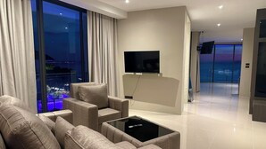 Een moderne woonkamer met een bank, een salontafel en een flatscreen televisie aan de muur.