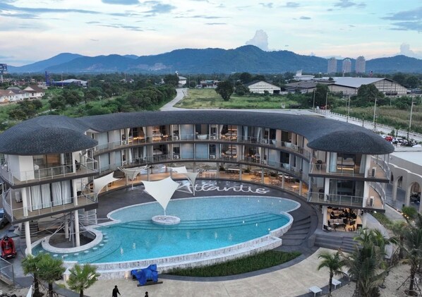 Un hotel con una piscina grande, varios balcones y vistas a las montañas.