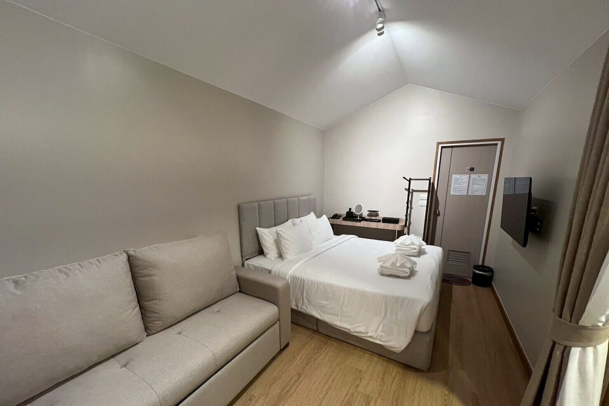 Une chambre à coucher comprenant un lit, un canapé, une télévision et un bureau avec une chaise.