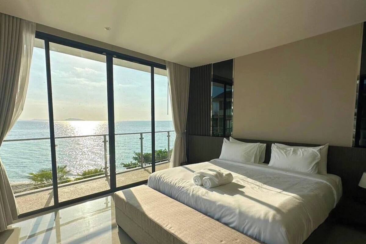 Une chambre spacieuse avec un grand lit, une vue sur la mer et un balcon.