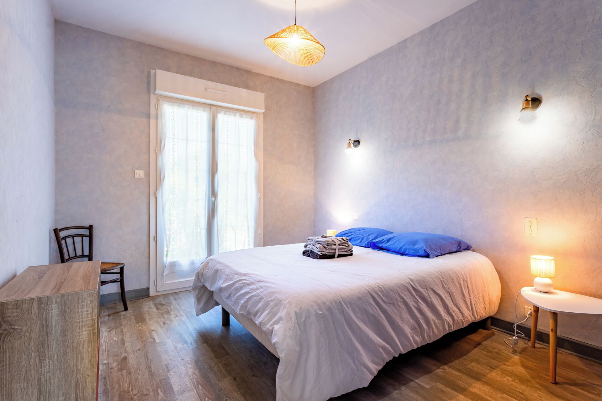 Ein Schlafzimmer mit Bett, Stuhl, Schreibtisch und Lampe.