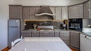 Una cocina moderna con armarios grises, un horno Bosch y una mesa con mantel blanco.