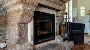 Una chimenea de piedra con puerta de vidrio negro, flanqueada por paredes de piedra y un suelo de baldosas.