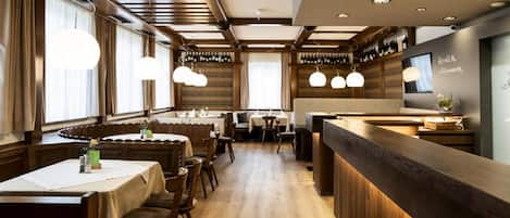 Ein Restaurant mit Holzwandverkleidung, Pendelleuchten und einer Bar.