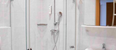 A modern bathroom with a glass-enclosed shower, a white sink, and a mirror above it.