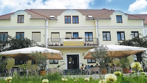 A restaurant with outdoor seating, a sign reading "Eisenbock's Spätsommerhof," and a building with a red-tiled roof. - Eisenbocks Strasser Hof (Straß im Straßertale)