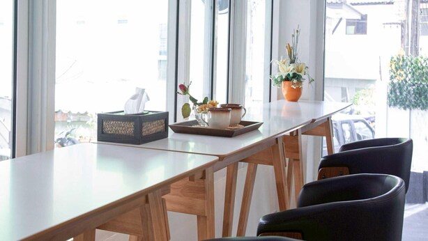 Un comedor moderno con una mesa larga, sillas negras y una ventana con vista a la calle.