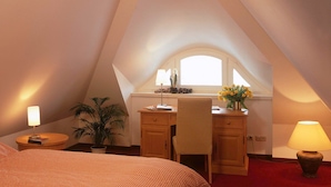 A bedroom with a bed, a desk, a chair, a lamp, and a window. - Kustenwaldvilla in Dierhagen (Ostseebad Dierhagen)